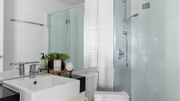 A modern bathroom with a large sink, mirror, toilet, and glass shower enclosure.