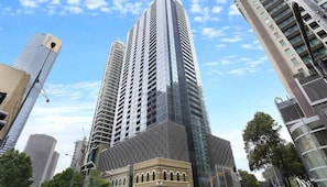 A high-rise building with a modern glass facade, surrounded by other tall buildings.