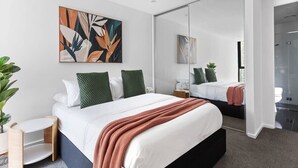 A modern bedroom with a large bed, a mirror, and a wall art piece. - Southbank 2BR Apt City Views, Free Parking (Southbank)
