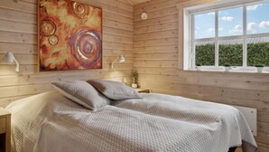Ein gemütliches Schlafzimmer mit einem großen Bett, einem Bild an der Wand und einem Fenster mit Blick auf Grünflächen.