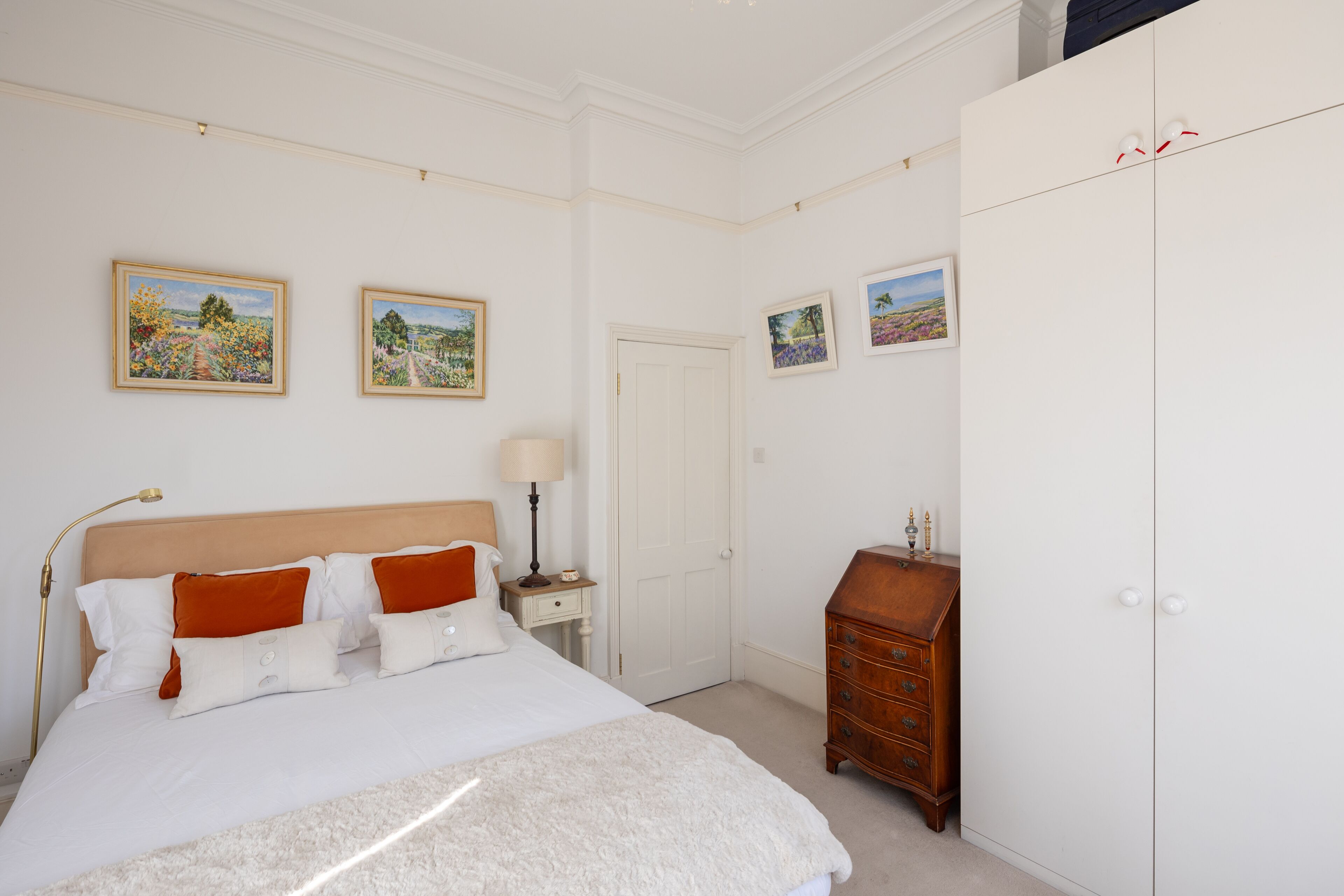 Een slaapkamer met een bed, een dressoir en een kledingkast.