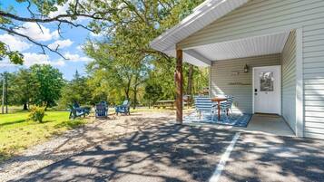 A covered outdoor seating area with tables and chairs, a gravel path, and a building with a door labeled "Lakeside B Cottage".