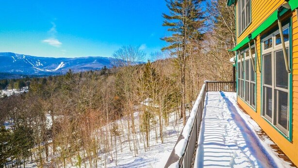 A yellow building with a green roof and large windows overlooking a snowy landscape with trees and mountains. - Vermont Post & Beam w/Hot Tub & Stunning Views (Waitsfield)