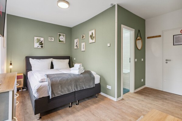 Un dormitorio con cama, mesita de noche y una puerta que da a otra habitación.