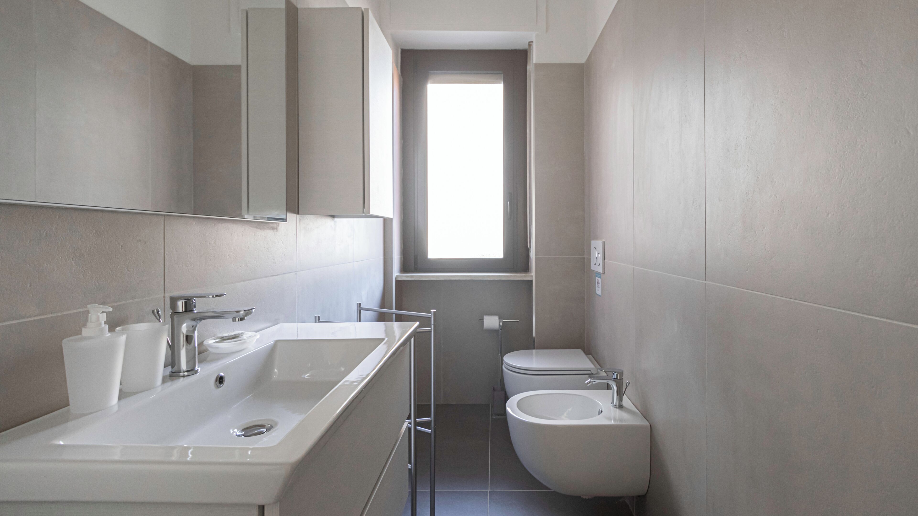 Un baño moderno con un lavamanos grande, espejo y bidé.