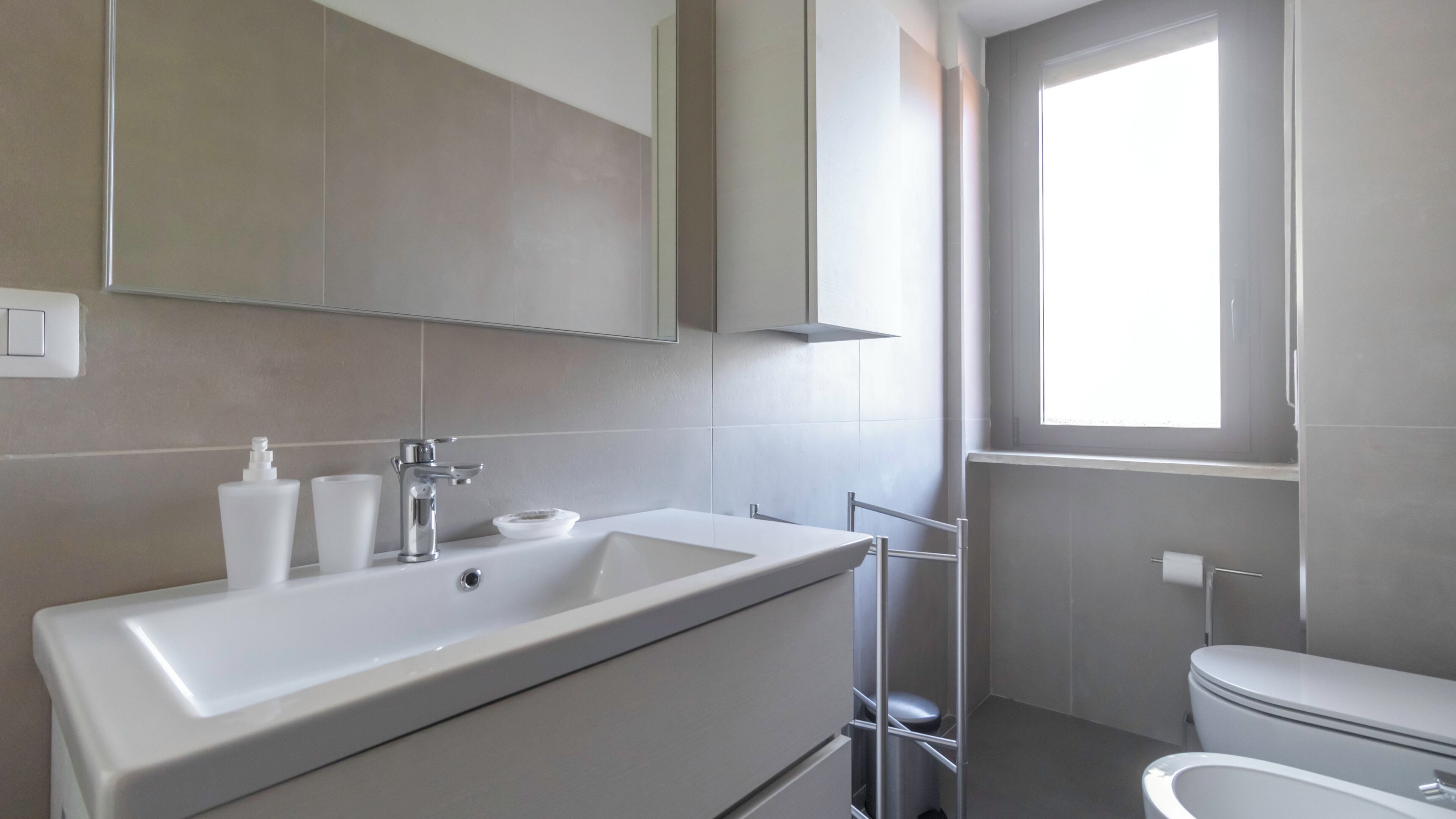 Een moderne badkamer met een groot wastafel, spiegel en toilet.