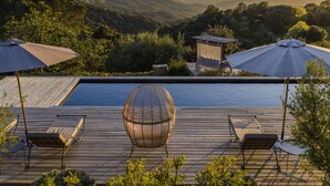 A poolside area with lounge chairs, umbrellas, and a spherical wicker chair. - Terre de Maquis (Sari-d'Orcino)