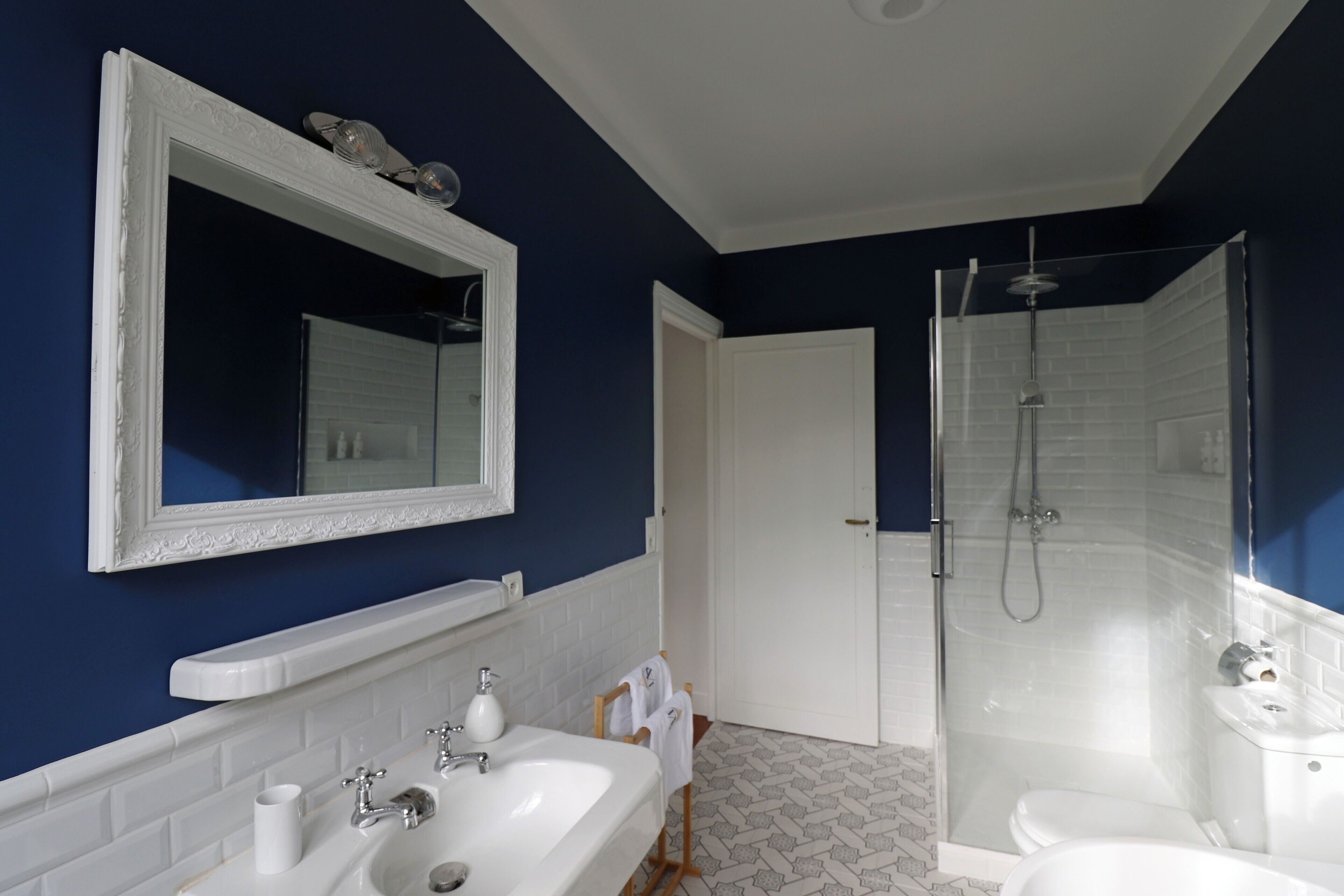 Een badkamer met een wit wastafel, spiegel en douche.