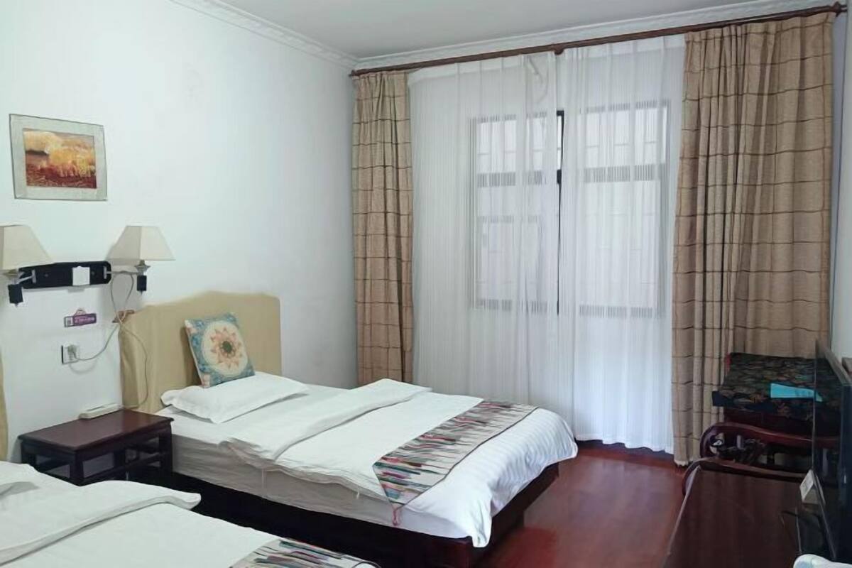 A hotel room with a bed, a bedside table, a lamp, a chair, and a television.