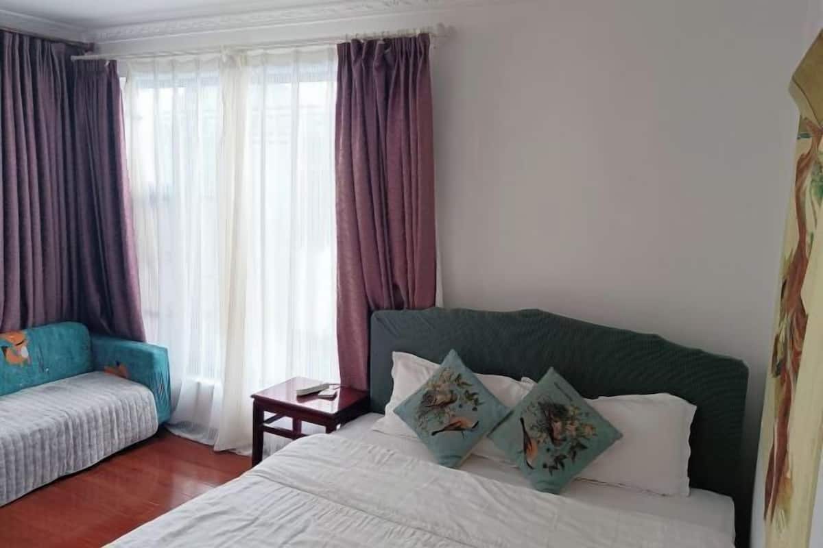 A hotel room with a bed, a sofa, and a small table.