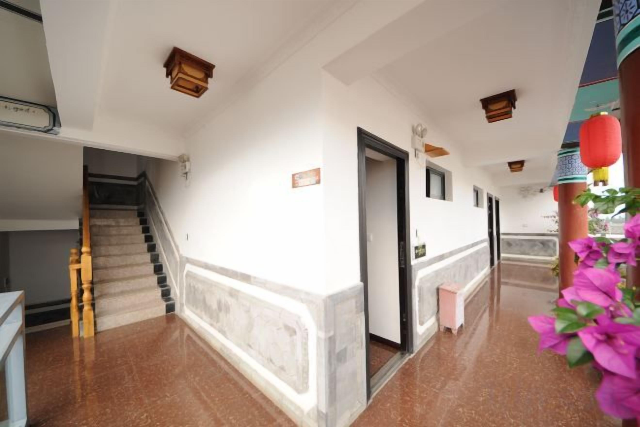 A hotel corridor with a staircase, a door, and a wall-mounted sign.