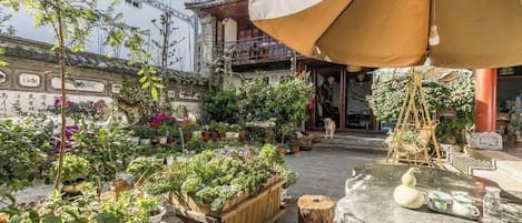 An outdoor garden area with potted plants and a table with a white vase.