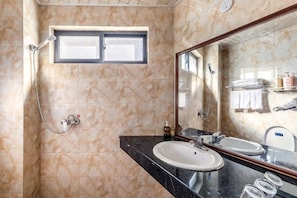A bathroom with two sinks, a shower, a window, and a mirror.