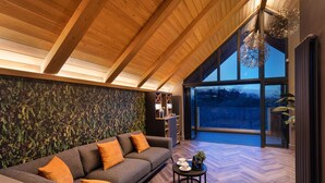 A modern living room with a wooden ceiling, a large window, and a grey sofa with orange cushions. - Stylish Northumberland retreat in the heart of Amble (Amble)