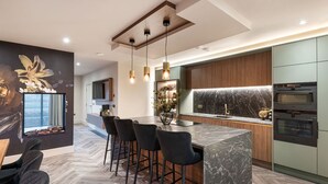 A modern kitchen with a marble island, pendant lights, and built-in appliances. - Stylish Northumberland retreat in the heart of Amble (Amble)