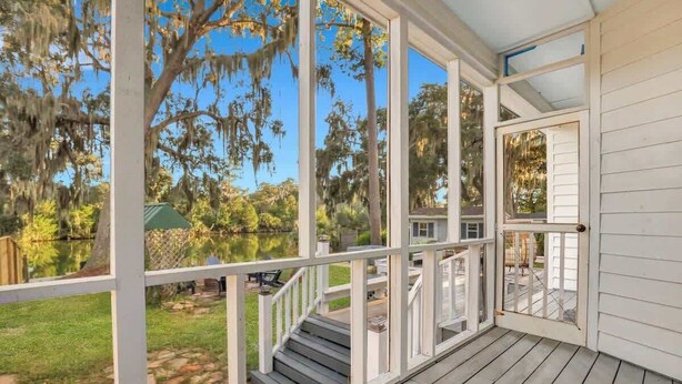 A covered porch with a view of a lake and trees.