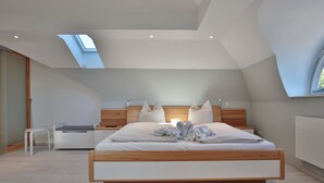 A modern bedroom with a skylight, a bed with white bedding, wooden headboard, and a bedside table. - Haus Schäfer Appartement 8 (Timmendorfer Strand)