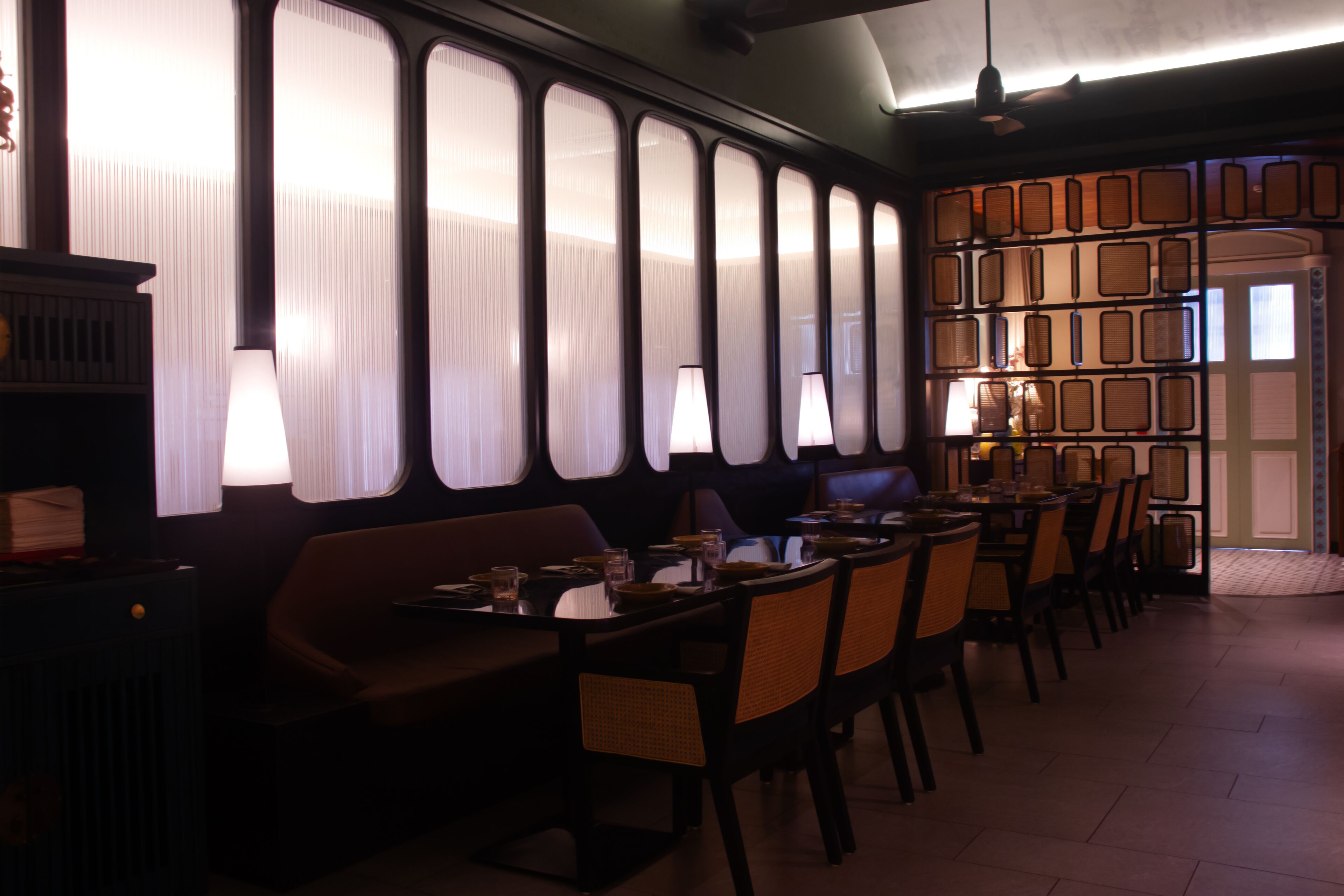 A restaurant with a long counter, cushioned seating, and a wall of framed pictures.