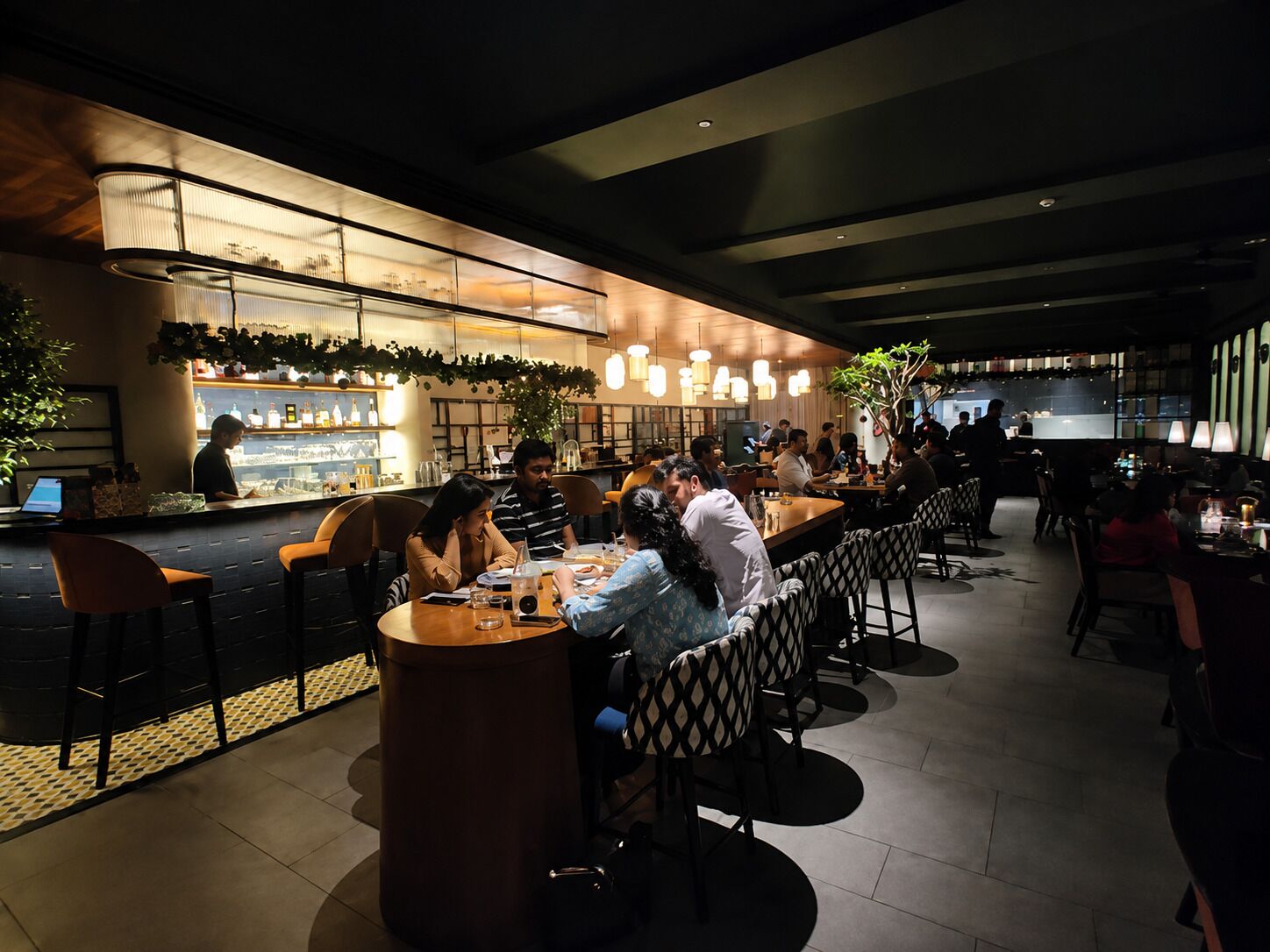 A modern restaurant interior with a bar area, seating arrangements, and a counter.
