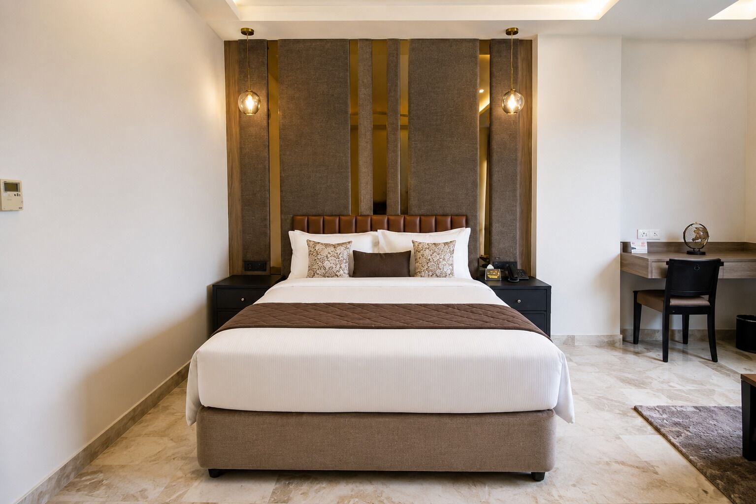 A hotel room with a large bed, a desk, and a chair.