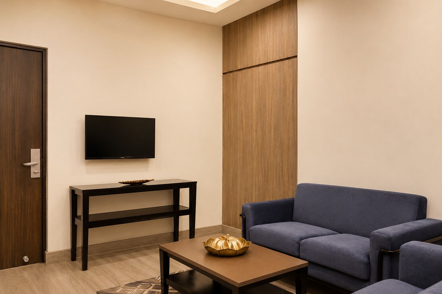 A room with a TV on the wall, a sofa, a coffee table, and a wooden panel.