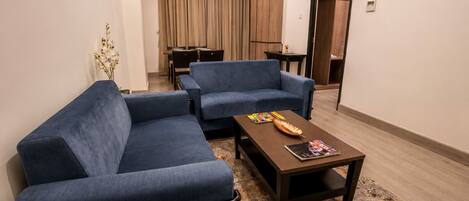 Una sala de estar moderna con un sofá seccional, una mesa de centro y un comedor al fondo.