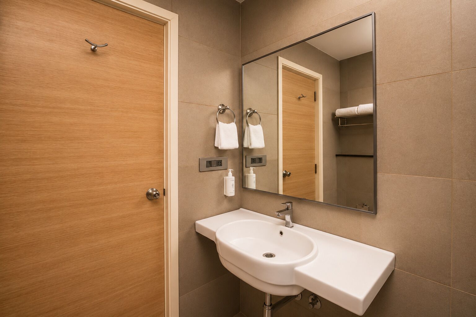 A bathroom with a wooden door, a white sink, a mirror, and a towel rack.