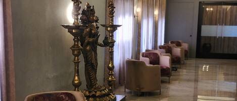 Un'elegante hall d'hotel moderna, con pavimento in marmo, comodi posti a sedere e statue decorative.