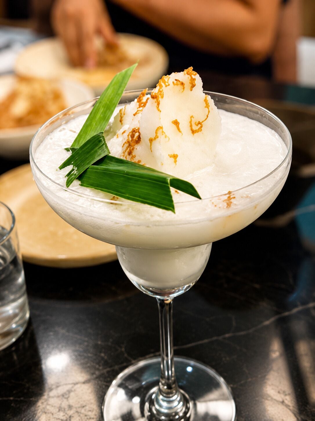 A dessert in a glass with a scoop of ice cream and a leaf garnish.