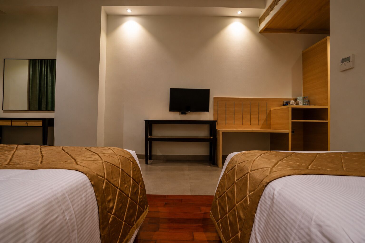 A hotel room with two beds, a television, a desk, and a wardrobe.