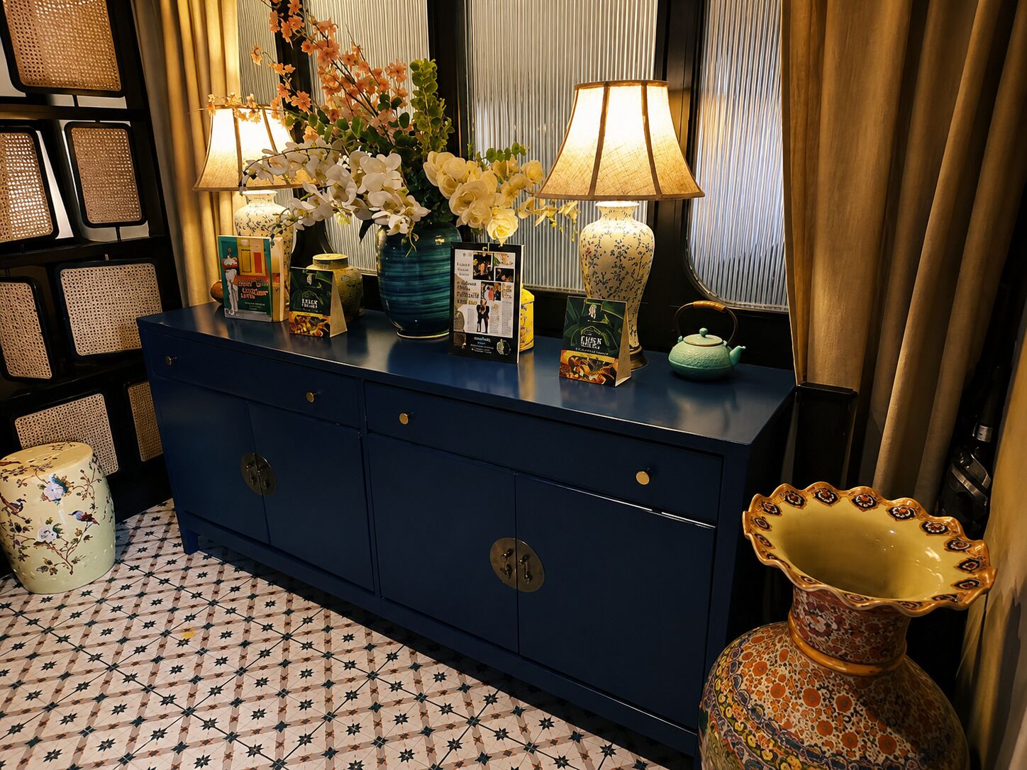 Une console bleue ornée d’objets décoratifs, une théière verte et un vase à motifs.