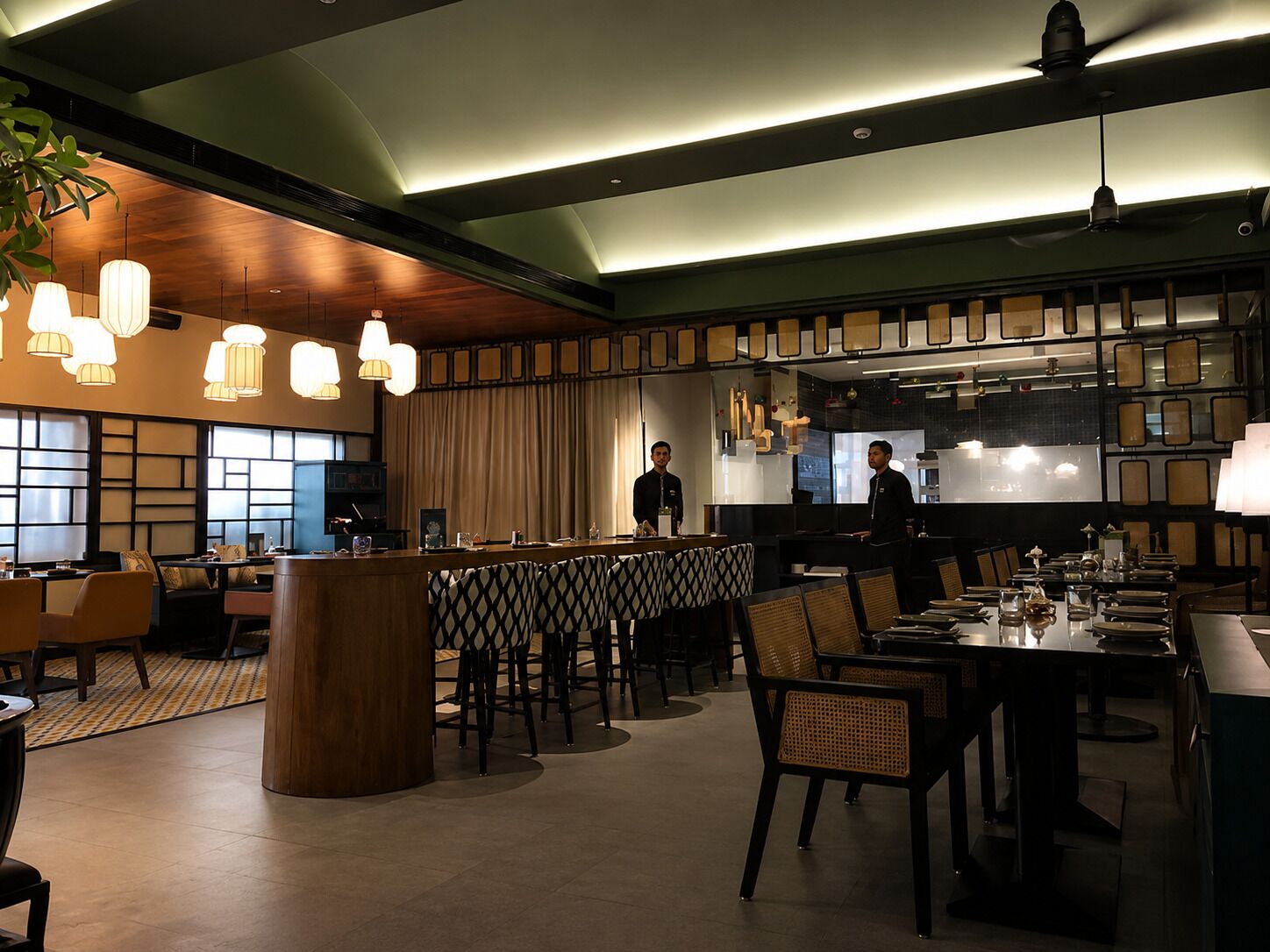 A modern restaurant with a bar area, wooden ceiling, and pendant lighting.