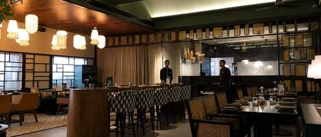 Ein modernes Restaurant mit Barbereich, Holzbalkendecke und Pendelleuchten.