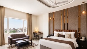 Una habitación de hotel moderna con una cama grande, un escritorio, un sofá y vistas a la ciudad.