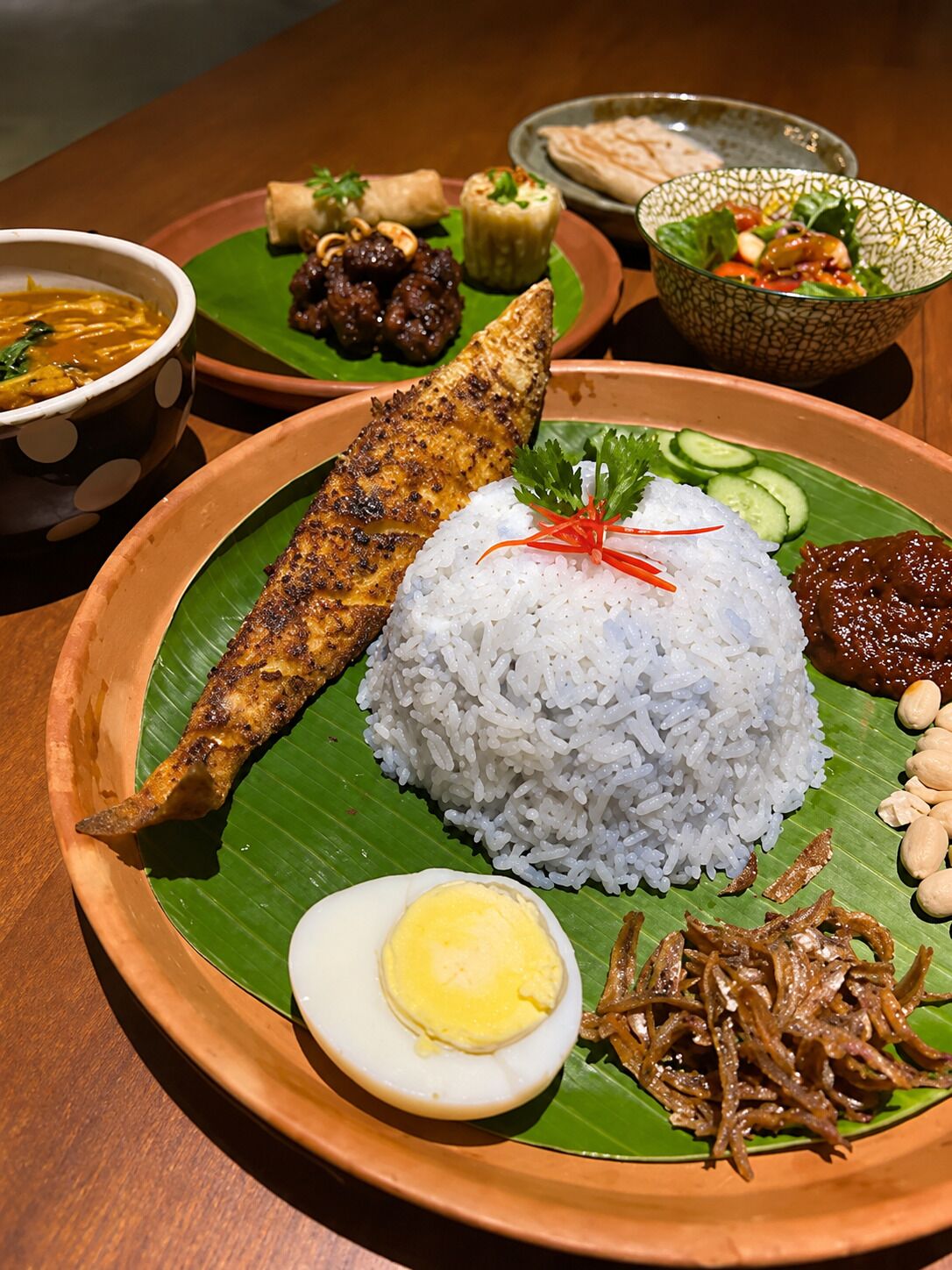 A plate of food with rice, a fish, a boiled egg, peanuts, and fried anchovies.