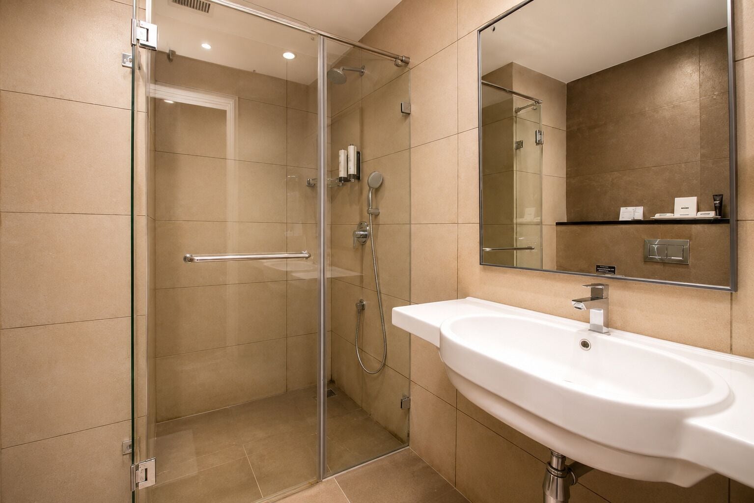 Un baño moderno con cabina de ducha de vidrio, un lavabo blanco y un espejo grande.