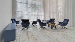 A modern conference room with a marble floor, a long table, and six blue chairs arranged around a central table. - Madeira Palace Ocean Sounds (Funchal)