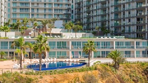 A modern hotel with multiple floors, a swimming pool, and palm trees. - Madeira Palace Ocean Sounds (Funchal)