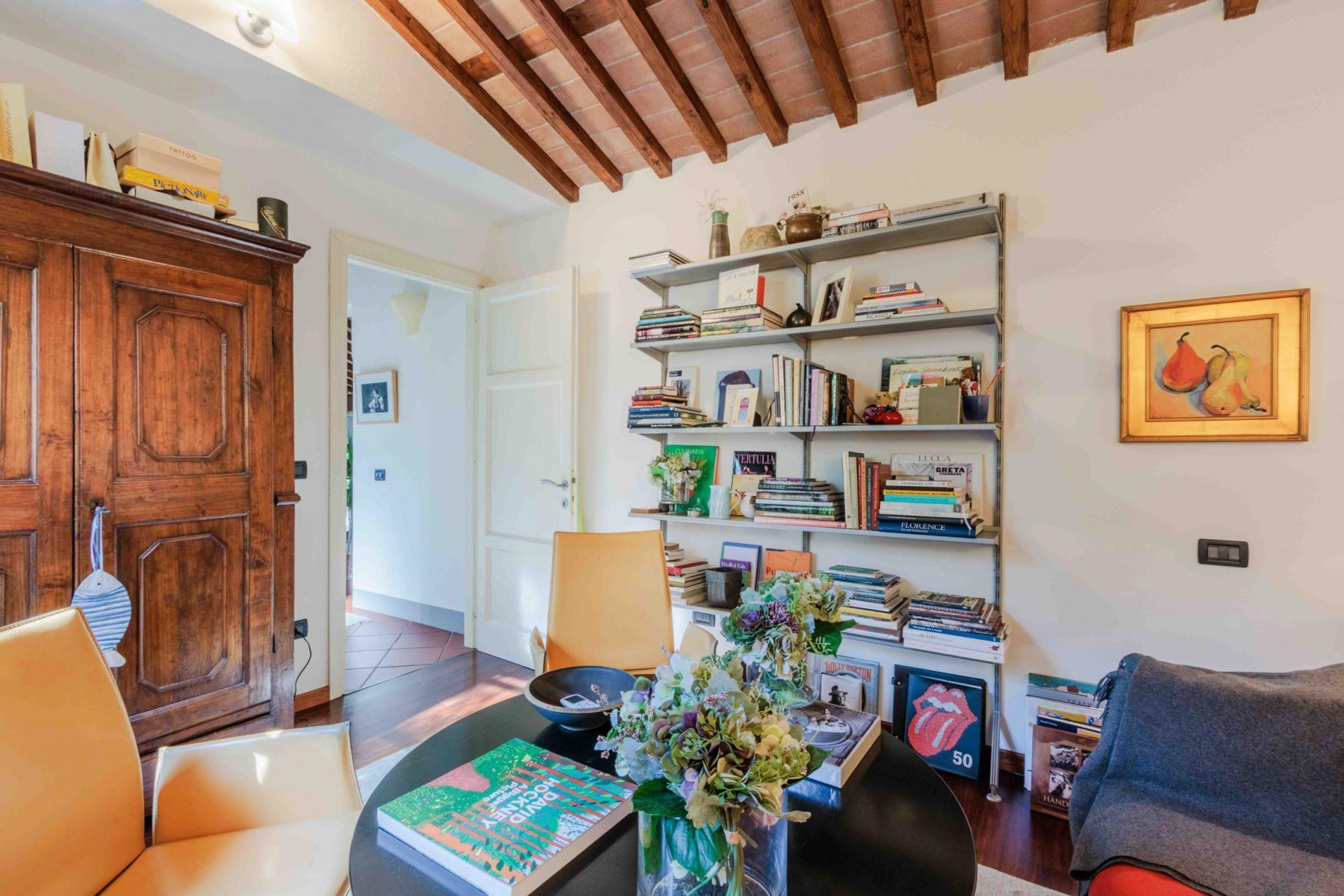 A cozy living room with a wooden cabinet, a bookshelf, and a framed picture on the wall.