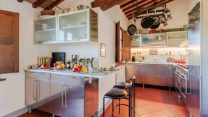 A modern kitchen with a central island, stainless steel appliances, and a rustic ceiling. - Villa Debby in Lucca (Lucca)