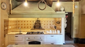 Una cucina con isola centrale, piano cottura a gas e zoccolo paraschizzi decorato.