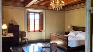 Una camera da letto con un letto di legno, una scrivania con una lampada, una sedia e una finestra illuminata dal sole.