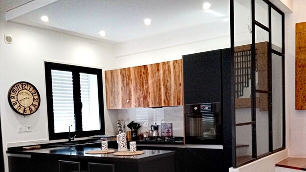 A modern kitchen with a central island, black bar stools, and a yellow ottoman. - Charme de L'atypique (Nabeul‎)