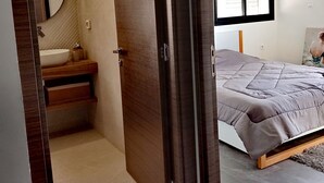A modern bedroom with a large bed, a bedside table, and a window with blinds. - Charme de L'atypique (Nabeul‎)