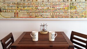 Une table à manger avec deux tasses portant l’inscription « Monsieur Parfait » et, sur le mur derrière, une grande fresque représentant une chronologie historique.