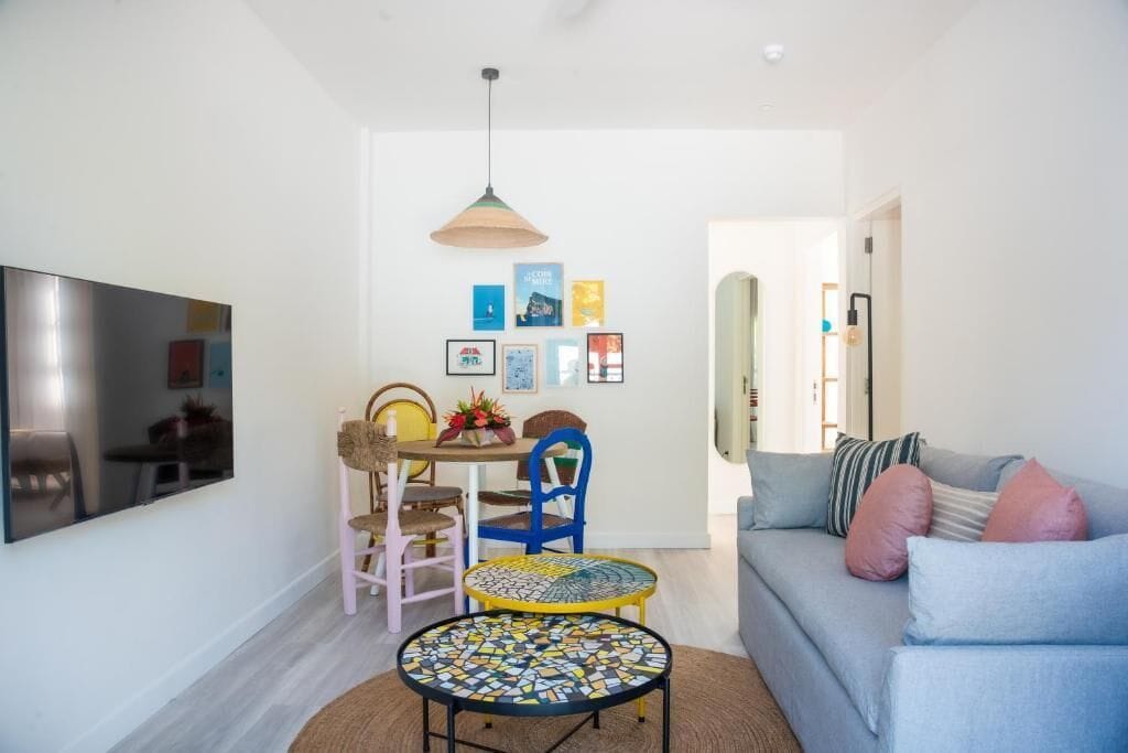 A living room with a sofa, a coffee table, and a dining area with chairs and a table.