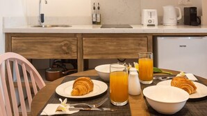 A modern kitchen with a sink, microwave, coffee maker, and a refrigerator. There is a dining table with plates of food and glasses of orange juice. - Dodo Square (Grand-Baie)