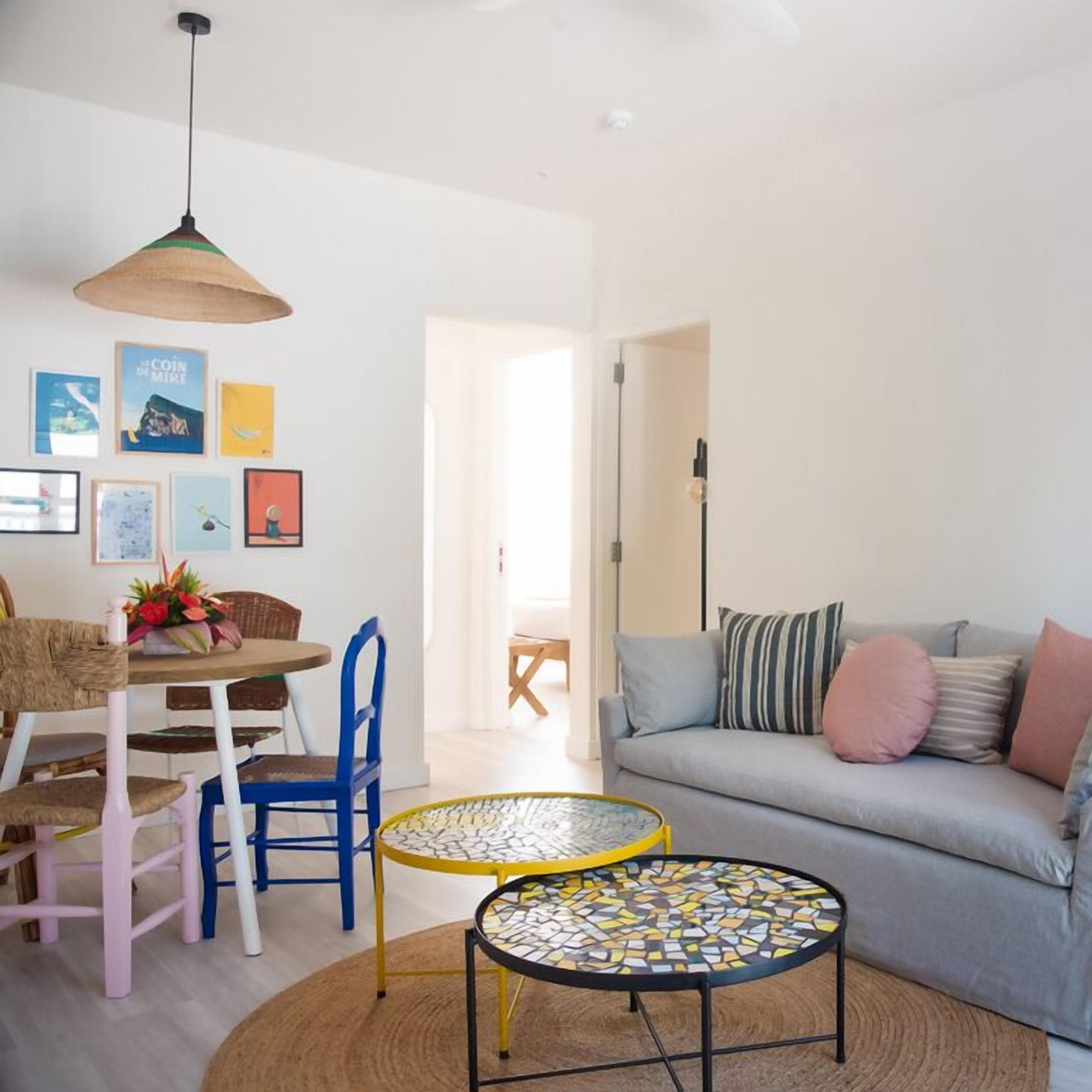 Una sala de estar con sofá, una mesa de comedor con sillas y una mesa de centro.