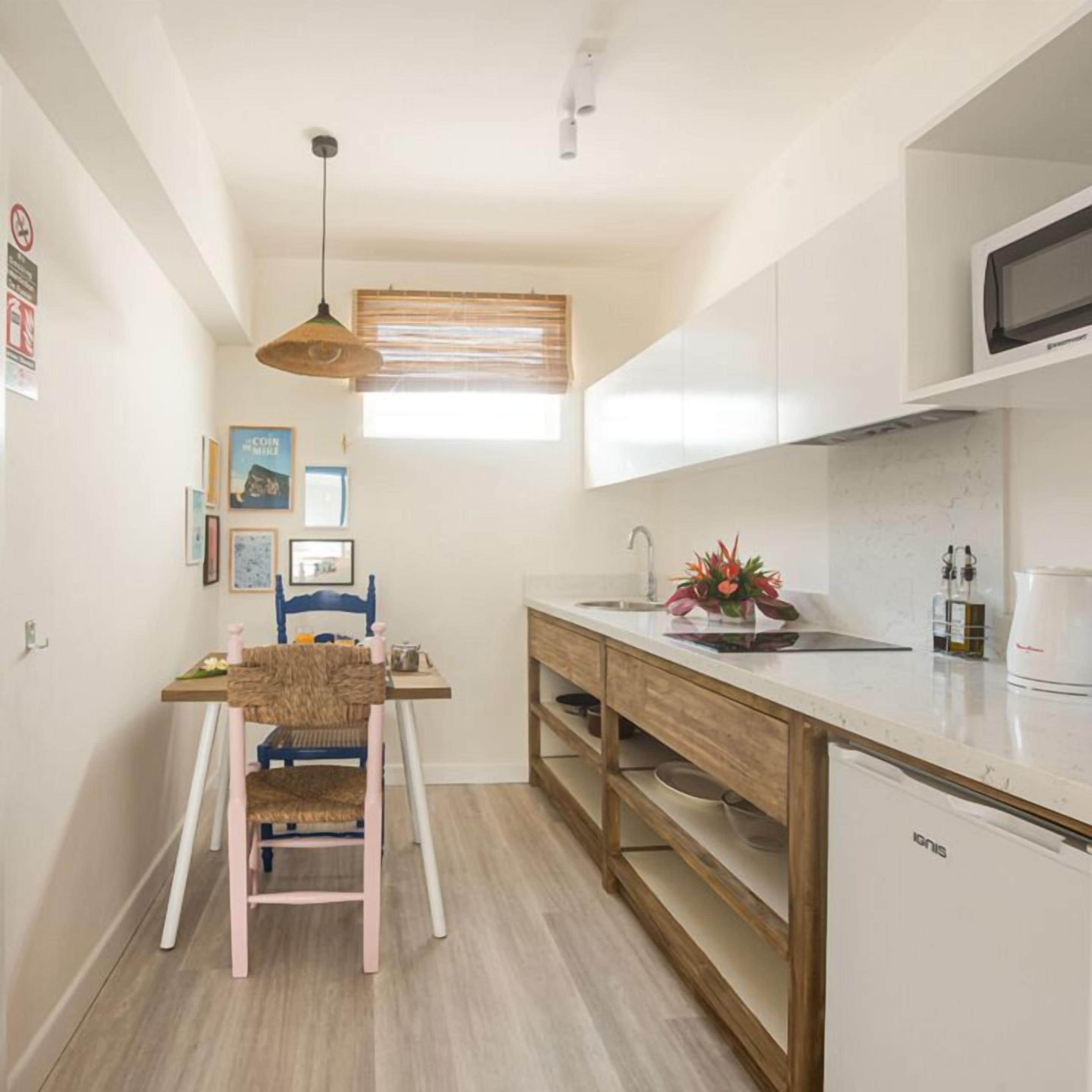 Una cocina compacta con una mesa de madera, una silla, un lavamanos y un microondas.