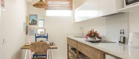 Una cocina compacta con una mesa de madera, una silla, un lavamanos y un microondas.